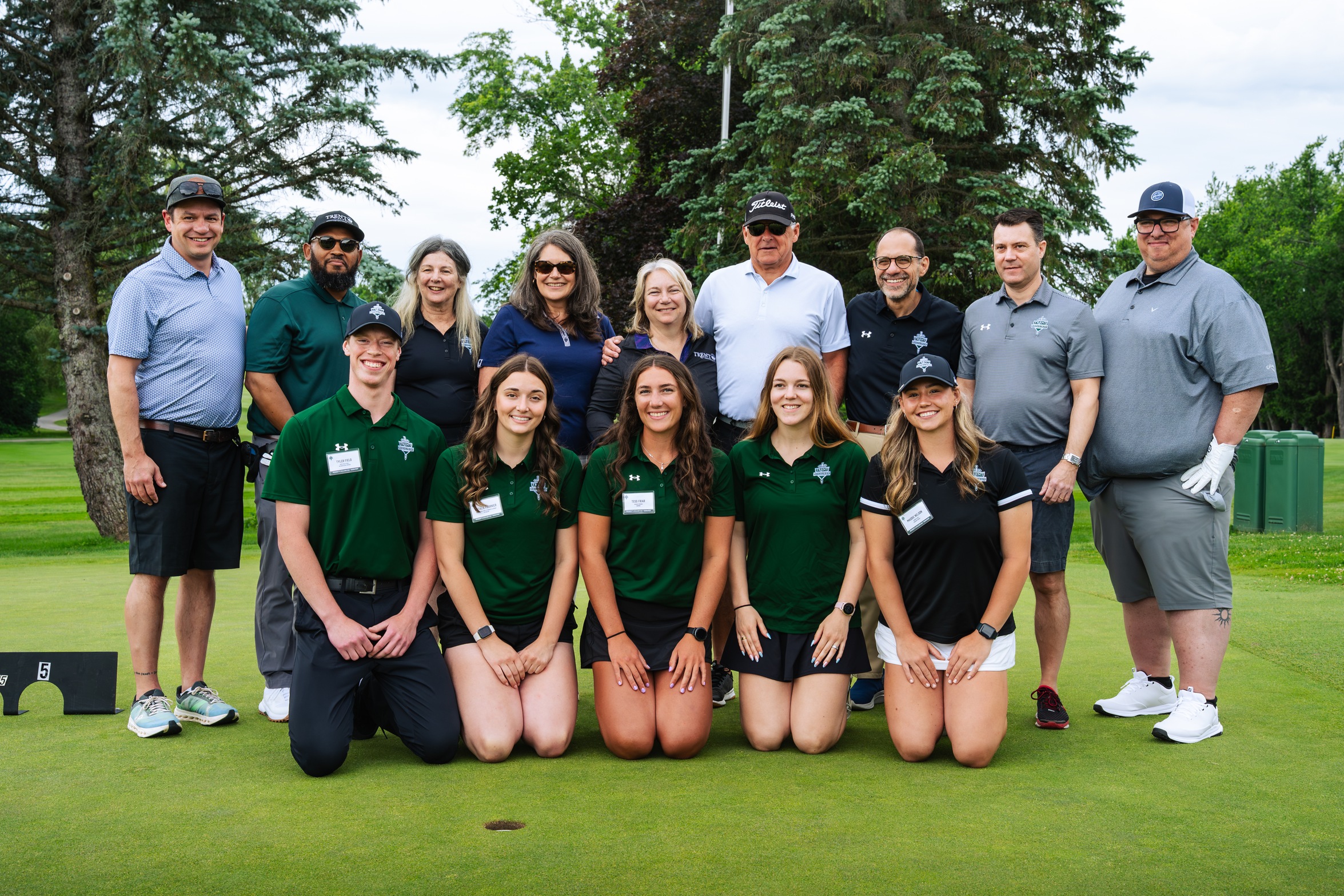 Participants in the President's Excalibur Golf Tournament pose on a putting green.