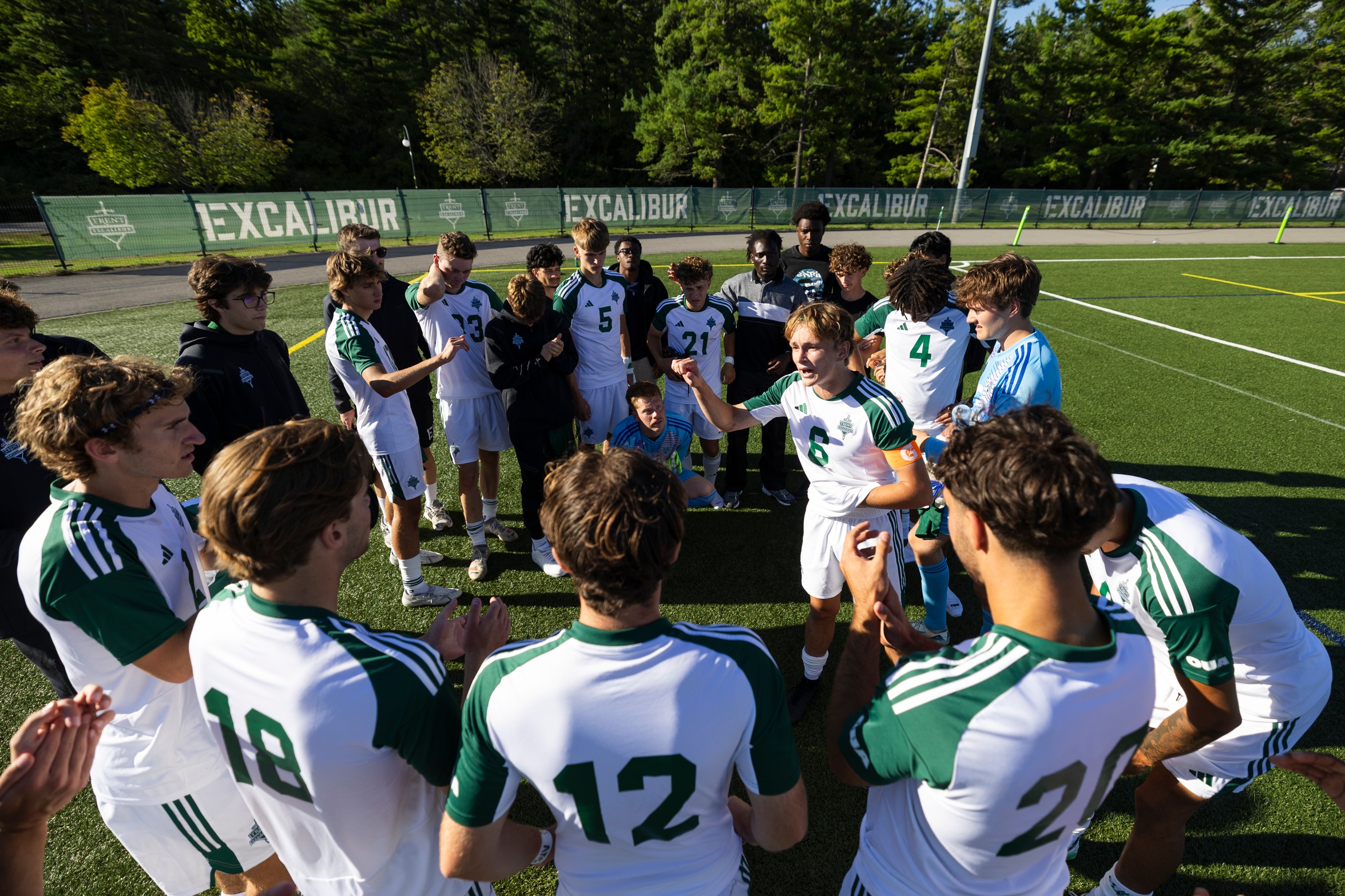 Excalibur men's soccer team in a huddle on the field